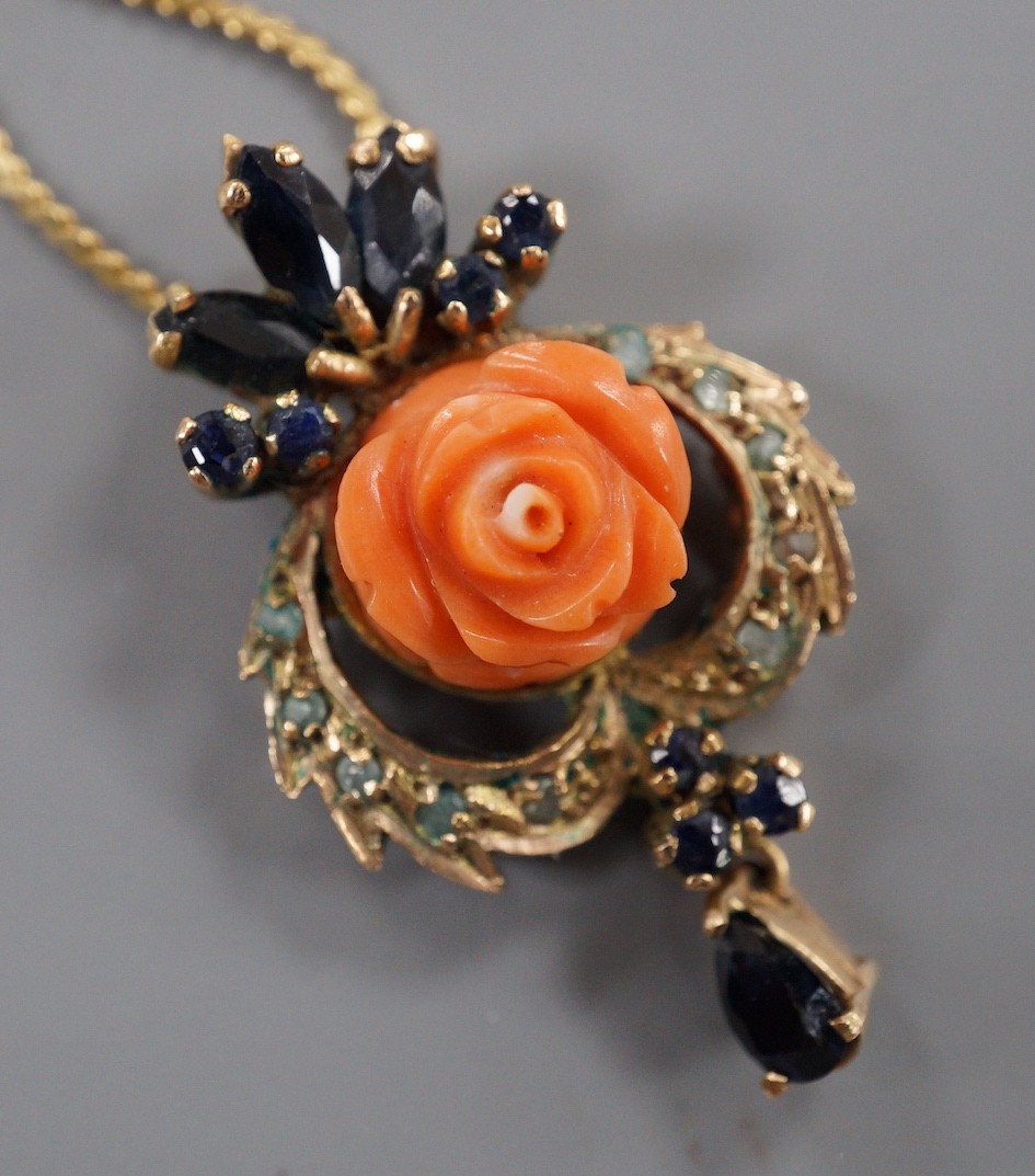 A 20th century yellow metal, carved coral, sapphire and gen set drop pendant, 32mm, on a later 750 chain, 38cm, gross weight 7.9 grams.